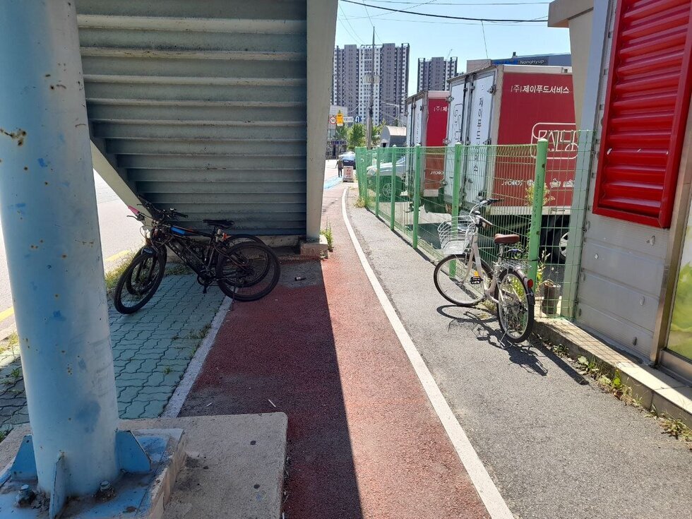 육교 밑에 가지런히 세워진 모범 자전거와 통로 울타리에  묶어 둔 모범되지 않은 자전거사례 사진입니다.