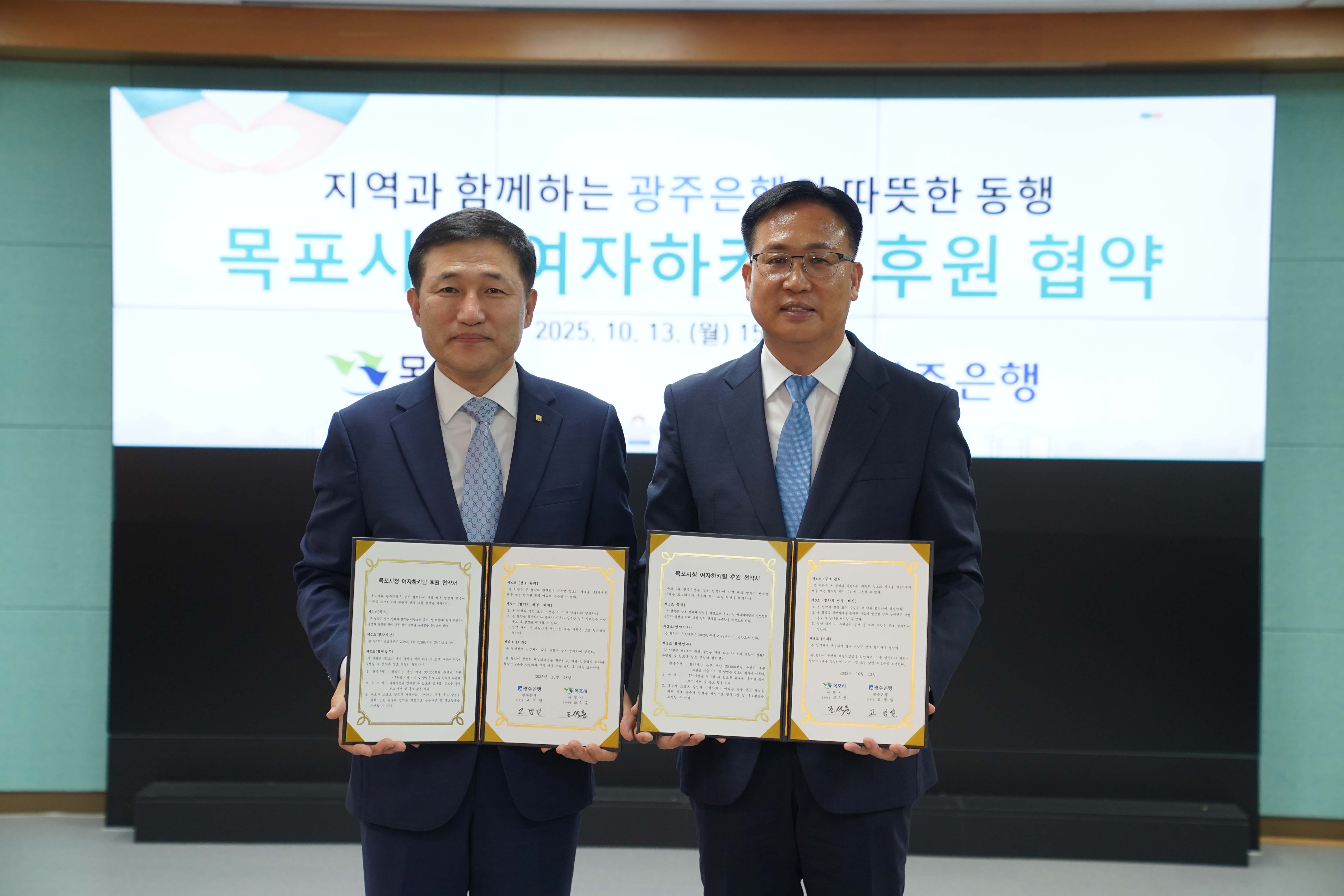 고병일 광주은행장과 조석훈 목포부시장이 서명된 '목포시청 여자하키팀 후원 협약서'를 각각 들고 기념 촬영을 하는 모습.